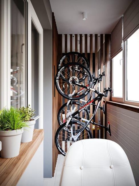 there is a bike rack on the wall in this room with plants and potted plants