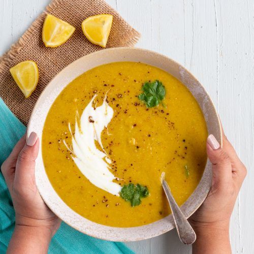 a person holding a bowl of soup with sour cream