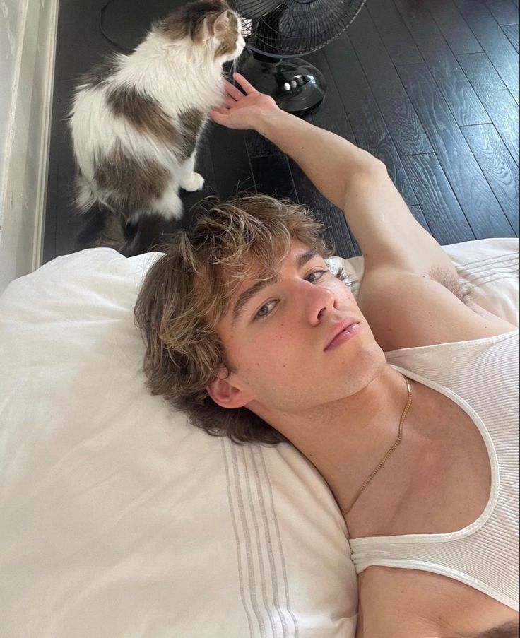 a man laying in bed next to a cat