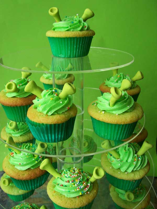 cupcakes with green frosting and sprinkles are arranged on a cake stand