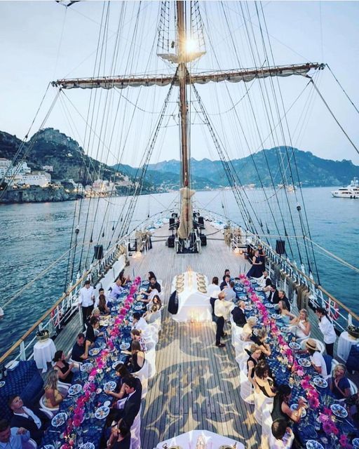 people are sitting at tables on the deck of a boat