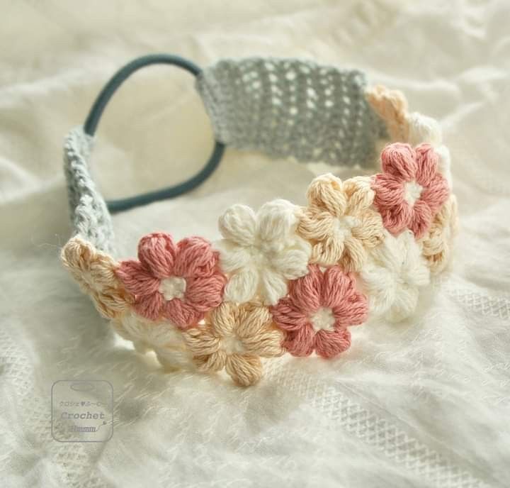 a crocheted headband with pink and white flowers