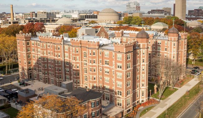 an aerial view of a large brick building in the middle of a city with tall buildings