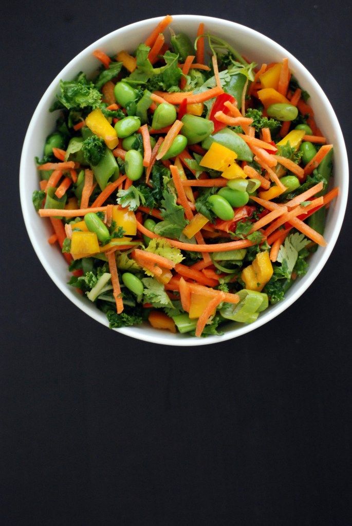 a white bowl filled with carrots, broccoli and other veggies