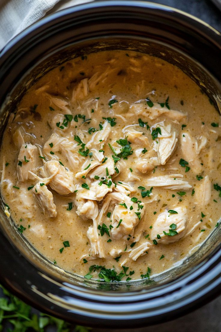 a crock pot filled with chicken and garnished with parsley on top