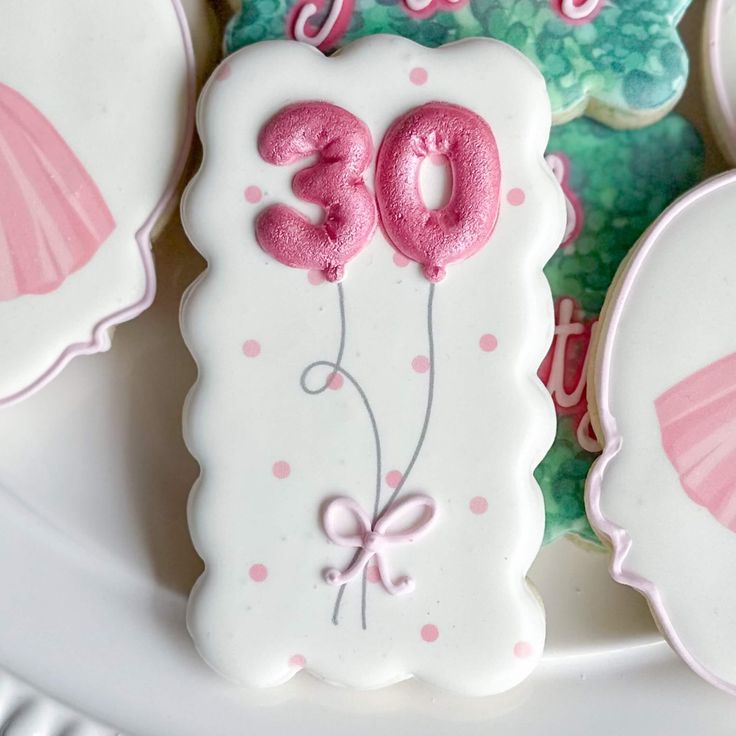 decorated cookies with pink and white icing are on a plate next to other decorations