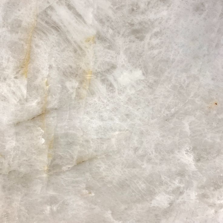 a white marble textured surface with yellow streaks on the left and right side, as seen from above