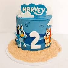 a blue two tiered birthday cake with cartoon characters on the top and bottom layer