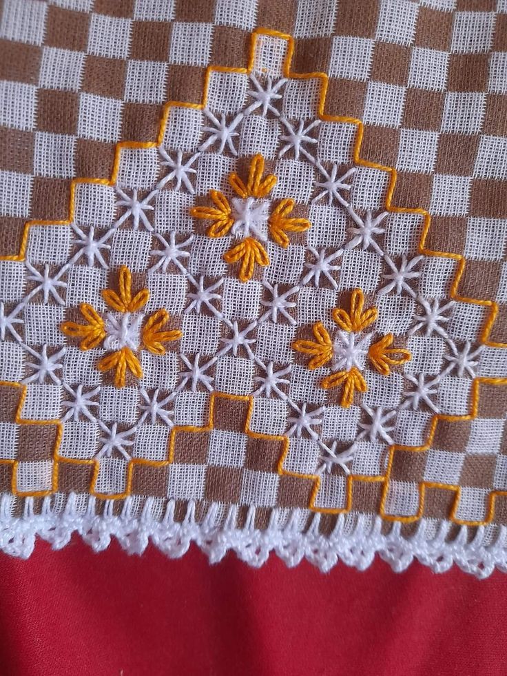 a close up of a piece of cloth with yellow and white crochet on it