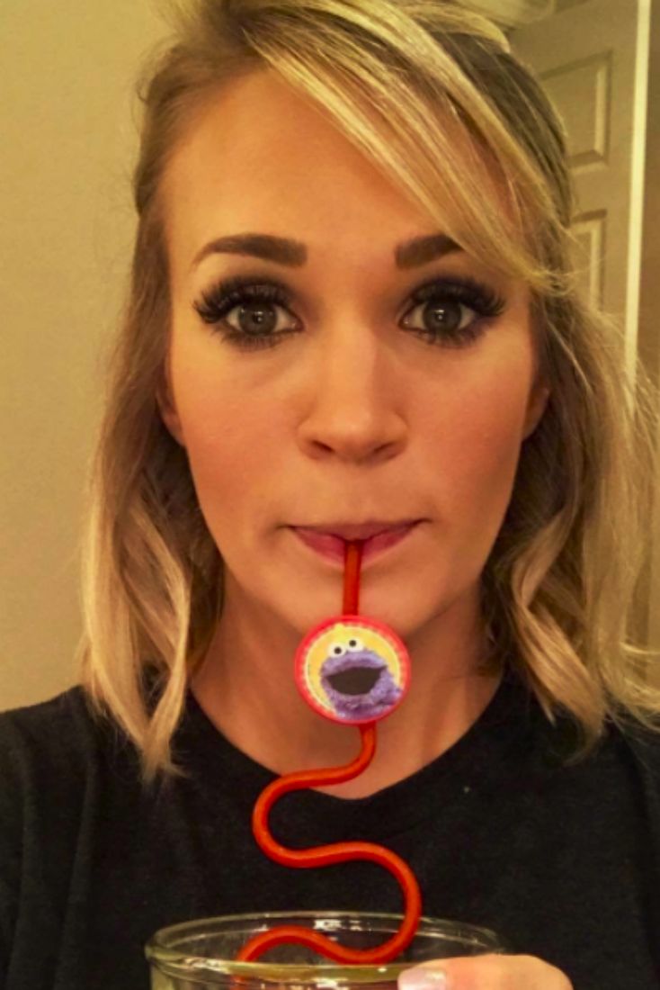 a woman holding a drink with a straw in it's mouth and an object sticking out of her mouth