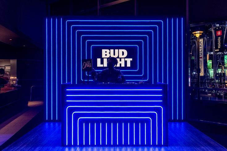 a blue lit room with neon lights in the background and an advertisement on the wall that says bud li'ht