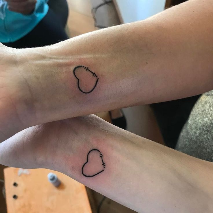 two people with matching tattoos on their feet, one has a heart and the other has a foot