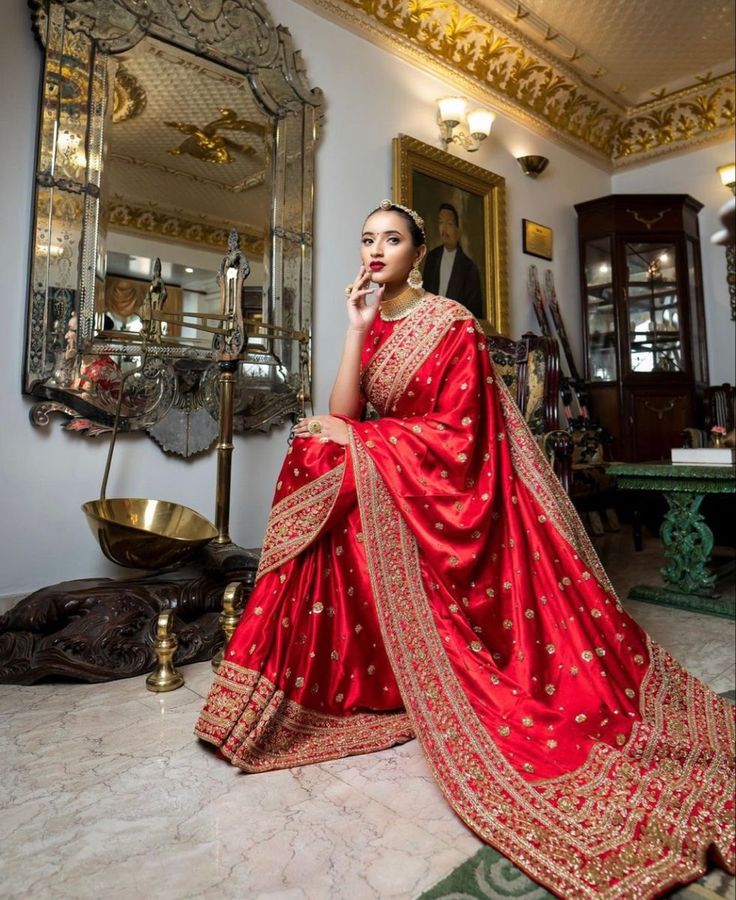 a woman in a red sari sitting on the floor with her hand under her chin