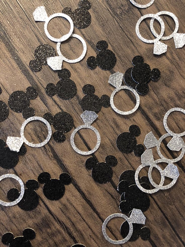 some black and white mickey mouse ears on a wooden table with glitter circles in the shape of rings