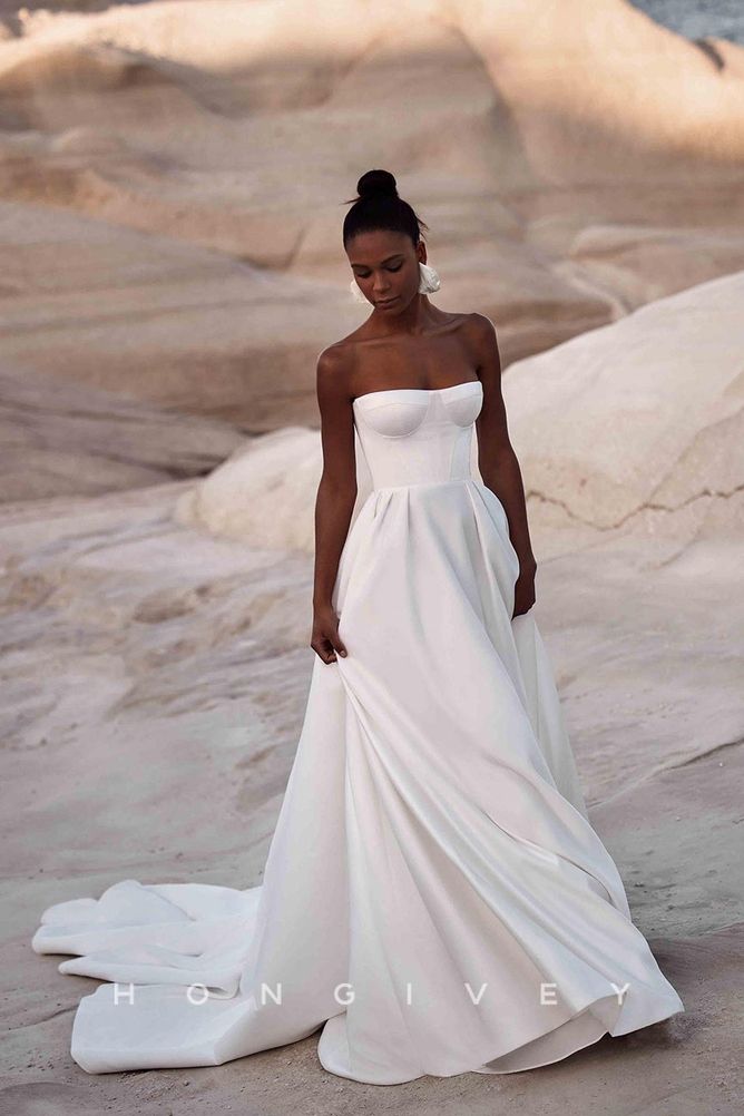 a woman in a white wedding dress standing on the beach with her hands in her pockets