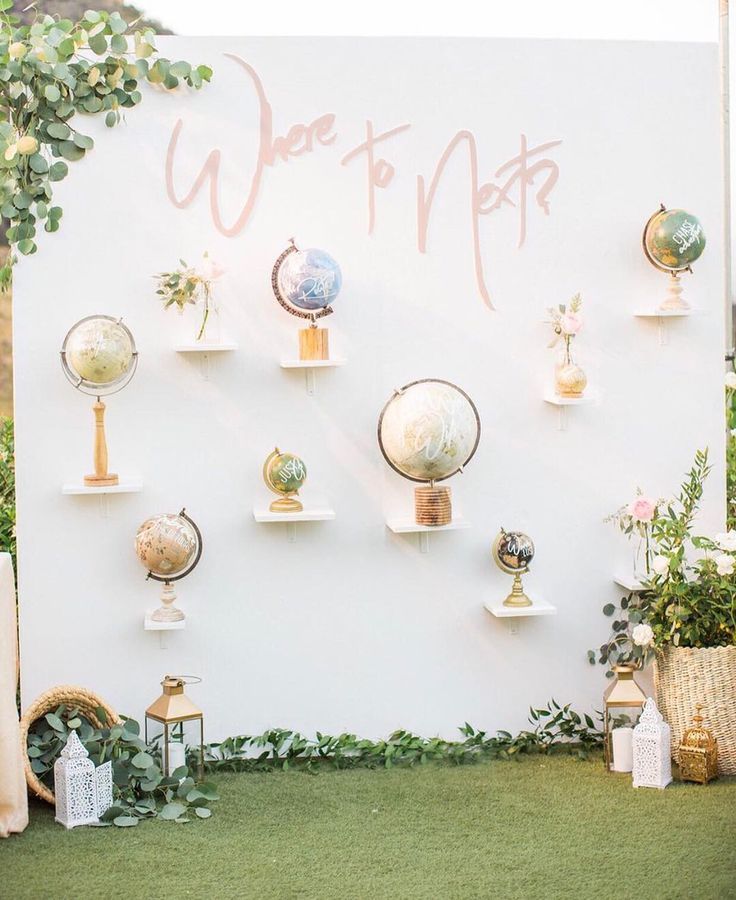 a white wall with lots of globes on top of it and greenery around the edges