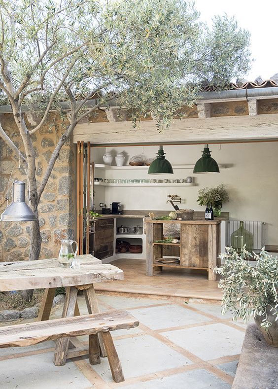 an outdoor kitchen and dining area is shown in this image, with wooden benches around the table