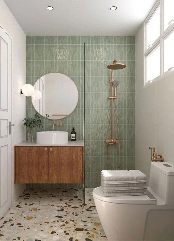 a white toilet sitting next to a bath tub under a bathroom mirror above a sink