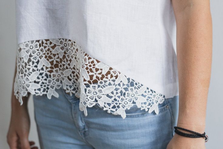 a close up of a person wearing jeans and a white shirt with lace on it