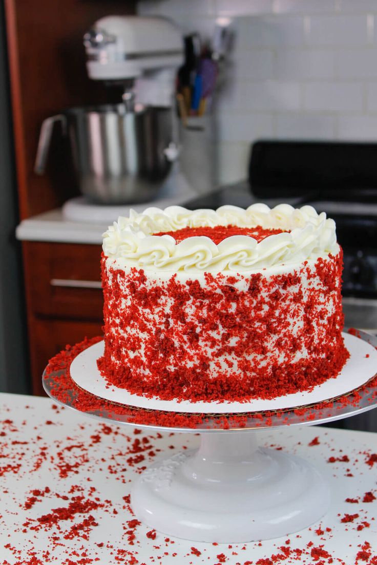 a red velvet cake with white frosting and sprinkles on a plate