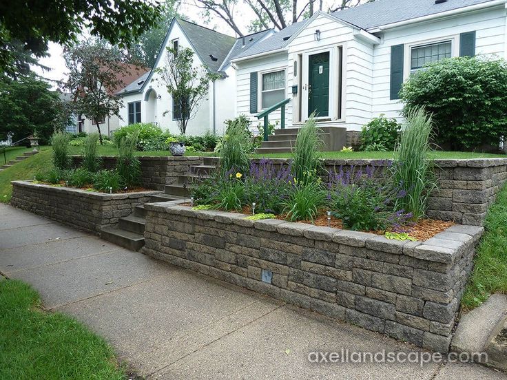 a stone wall and flower bed in front of a house