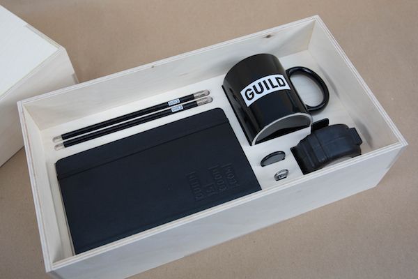 an open box containing a coffee mug, notebook and other items