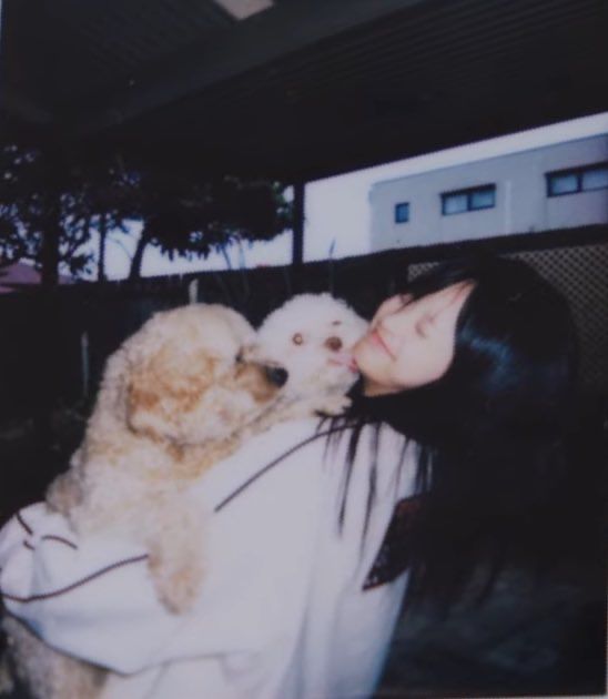 a woman holding a dog in her arms and kissing it's face with both hands