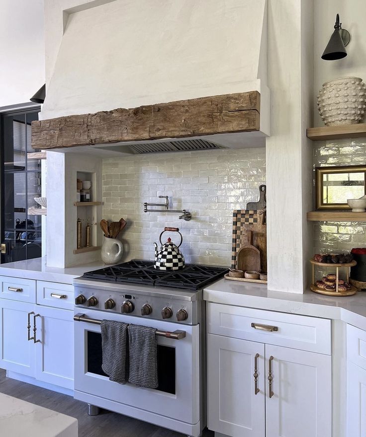 a stove top oven sitting inside of a kitchen next to white cupboards and shelves