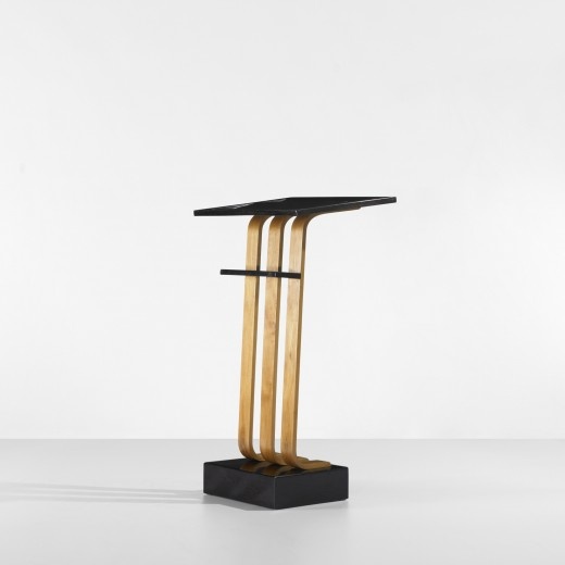 a black and gold table with three wooden bars on it's legs, in front of a white wall