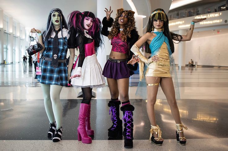 four women dressed up in costume posing for a photo together at an airport lobby area