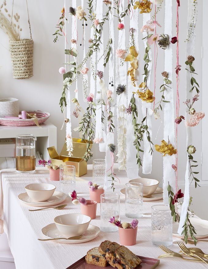 a white table topped with plates and cups filled with desserts next to hanging flowers