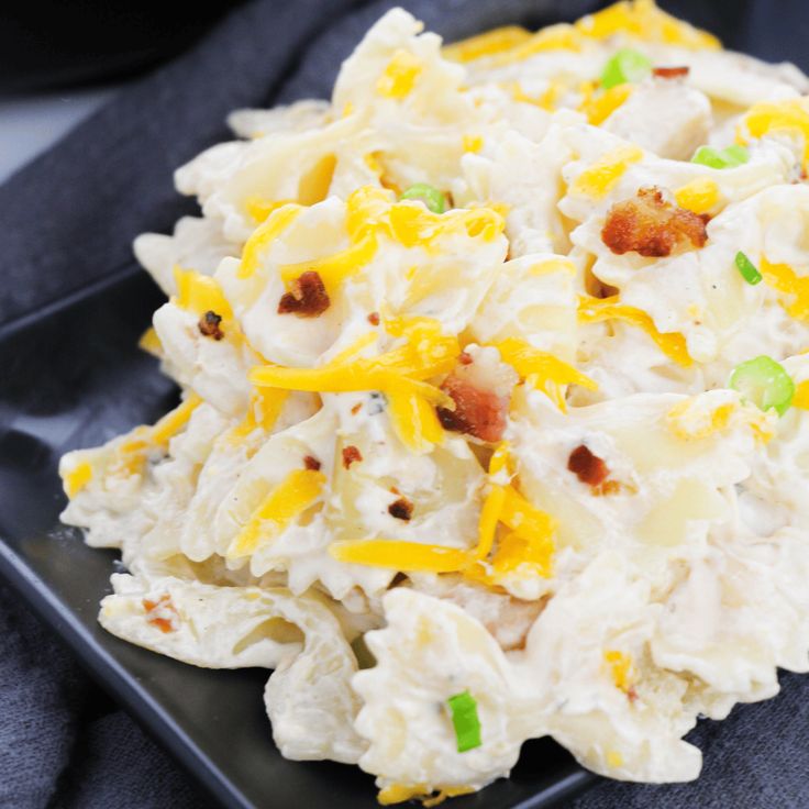 a black plate topped with potato salad on top of a table