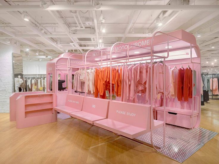 a pink display case with clothes hanging on it's sides and shelves in the middle