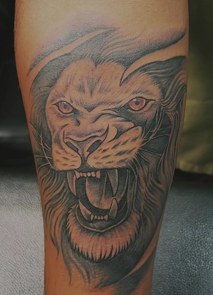 a man's leg with a tattoo of a lion and his mouth is open