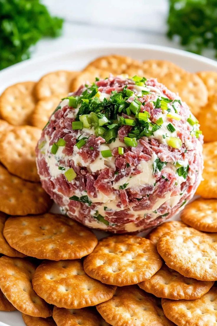 a cheese ball is on top of crackers and garnished with green onions