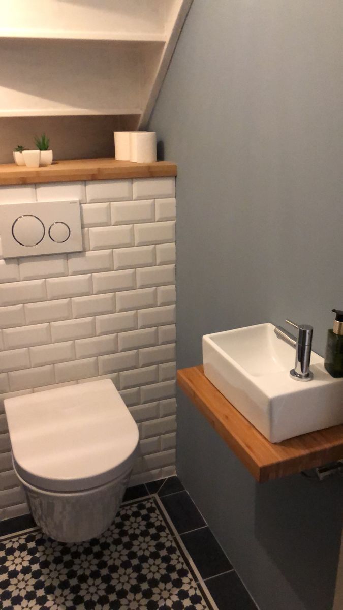 a white toilet sitting next to a sink in a bathroom under a slanted ceiling