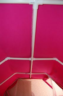 the inside of a pink tent with white piping