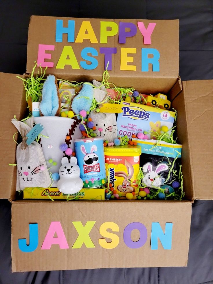 a box filled with candy and stuffed animals on top of a bed next to a sign that says happy easter