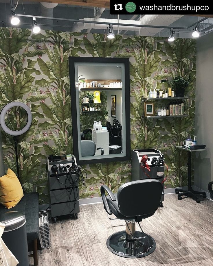 a hair salon with chairs, mirrors and shelves on the wall in front of it