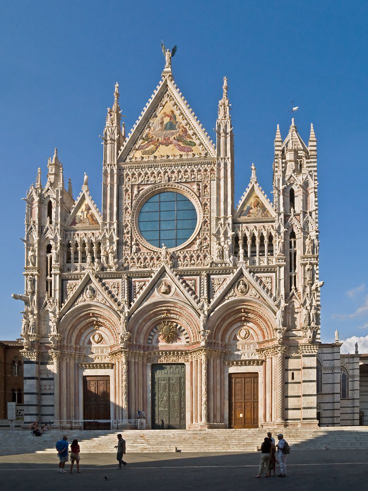 people are standing in front of an old church with tall towers and arched doorways