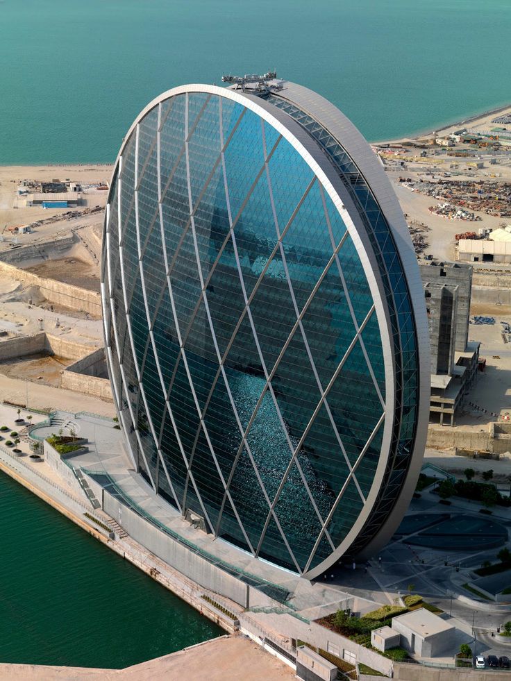 an aerial view of a modern building in the middle of a large body of water