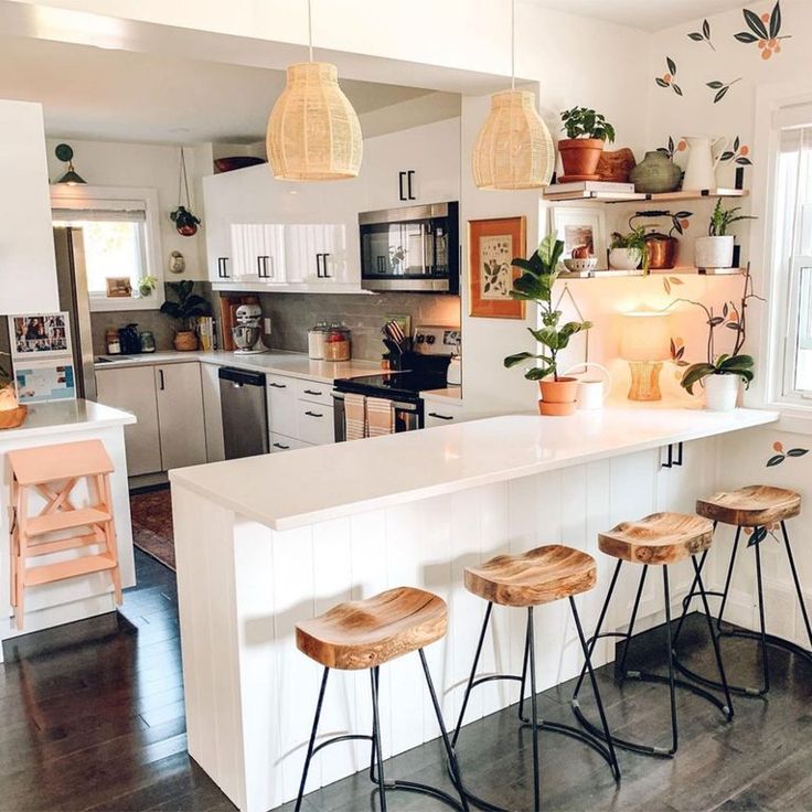 a kitchen with three stools in front of an island and several potted plants on the counter