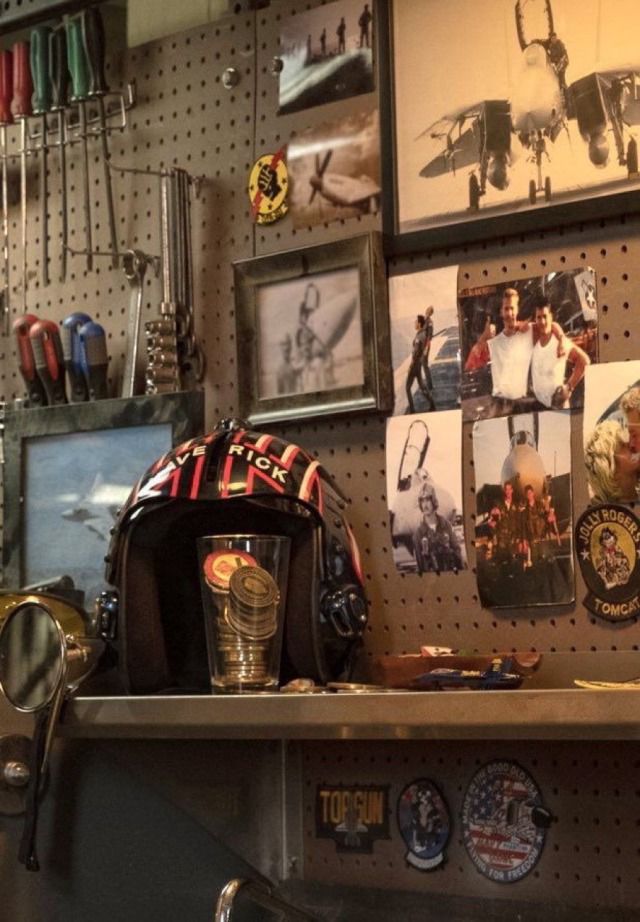 there are many pictures on the wall above the shelf in this shop, including an army helmet and other memorabilia