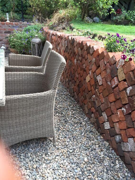 some chairs are sitting in front of a wall made out of bricks and gravels