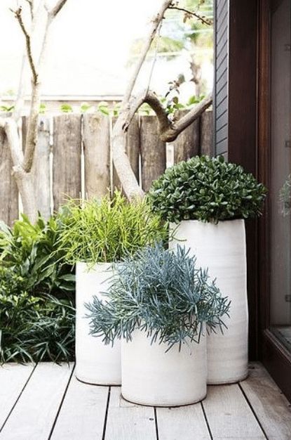 two white planters sitting on top of a wooden deck