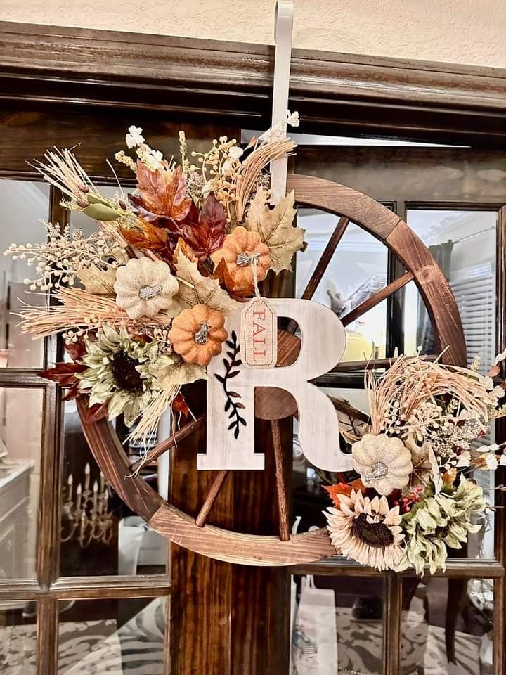 a wooden wheel decorated with fall flowers and a letter b on the front of it