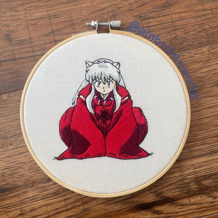 the embroidery pattern shows a woman in red dress with white hair sitting on her knees