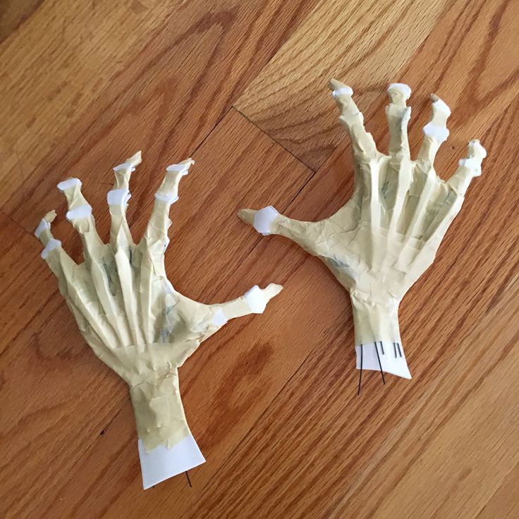 two fake hands are sitting on the floor next to each other, one is made out of paper