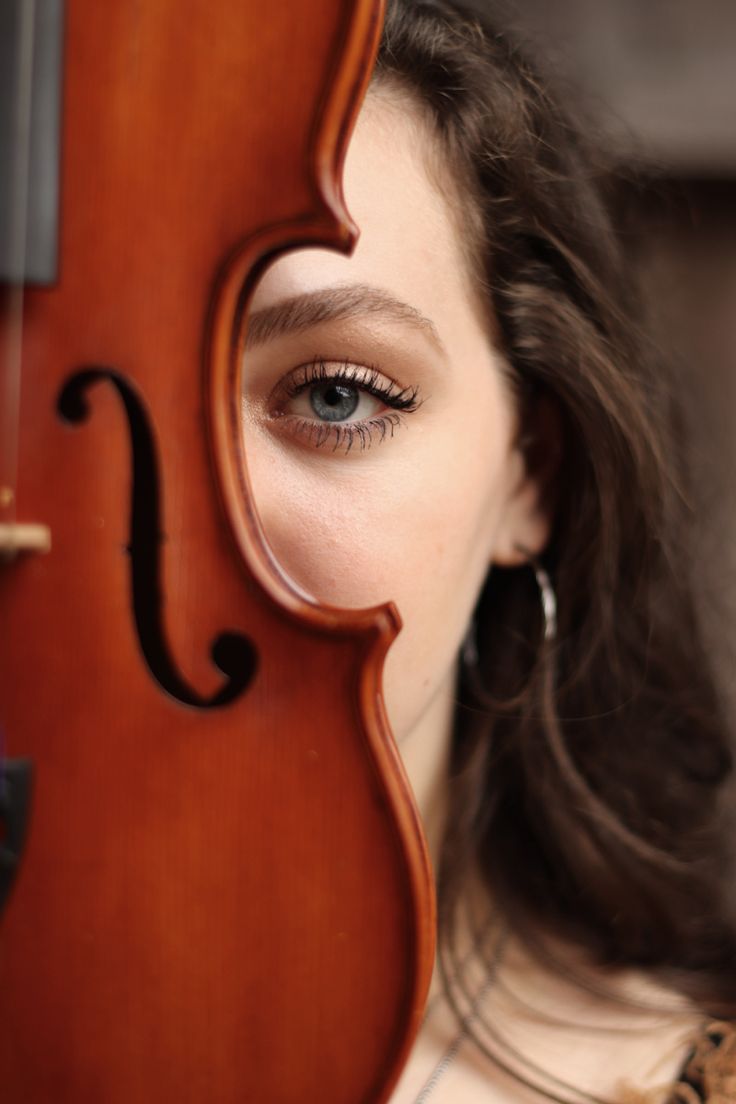 a close up of a person holding a violin in front of their face and looking at the camera