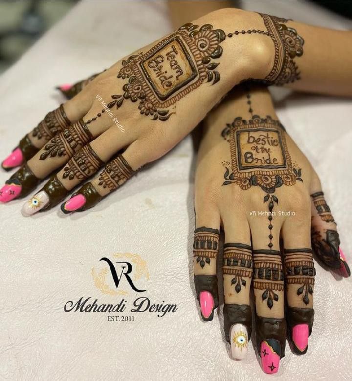 two hands with henna designs on them sitting on a white tablecloth covered table